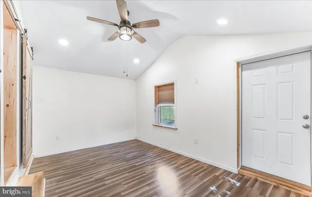 en empty room with wooden floor ceiling fan and windows