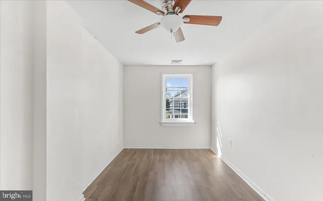 an empty room with a window and a ceiling fan