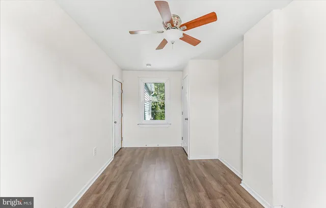 an empty room with wooden floor fan and windows