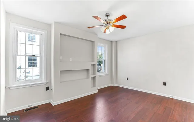 an empty room with wooden floor closet and windows