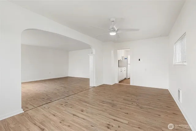 a view of empty room with wooden floor and fan