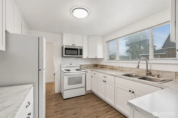 a kitchen with granite countertop white cabinets and white appliances