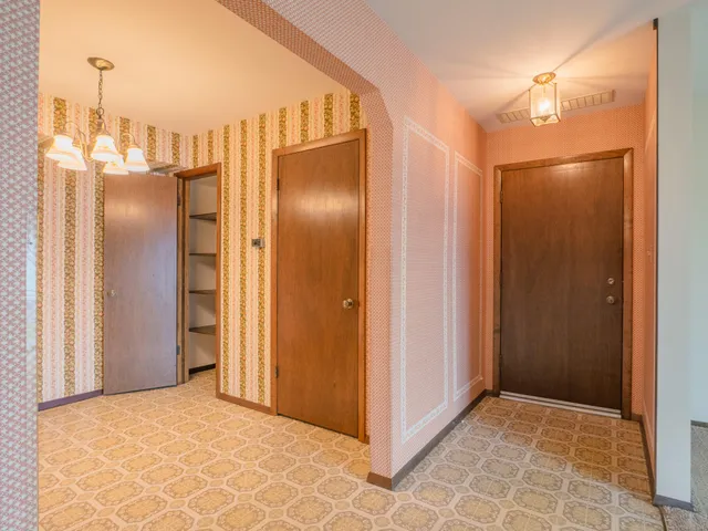a view of a refrigerator in kitchen and an empty room
