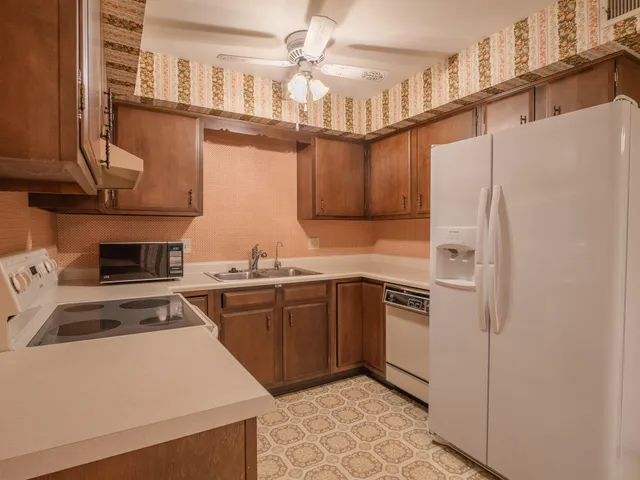 a kitchen with stainless steel appliances granite countertop a refrigerator a sink dishwasher a stove and a dining table with wooden floor