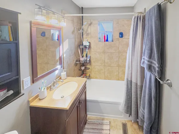 a bathroom with a sink a mirror a bathtub and shower