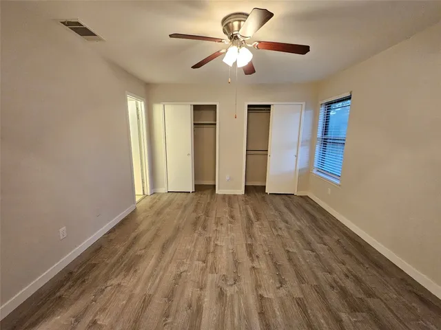 a view of empty room with wooden floor and fan