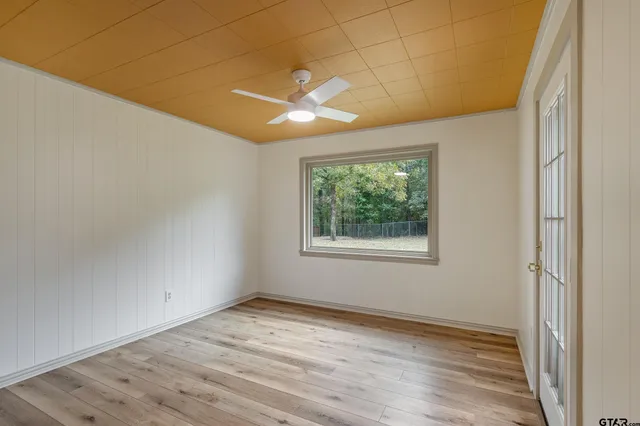 an empty room with wooden floor and windows