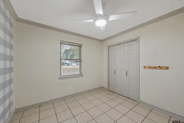 a view of an empty room with window and chandelier fan