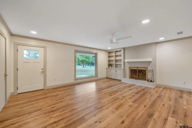 an empty room with wooden floor fireplace and windows