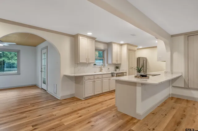 a kitchen with stainless steel appliances kitchen island wooden floors and white cabinets