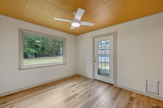 a view of an empty room with wooden floor and a window