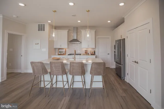 a dining area with stainless steel appliances kitchen island granite countertop a dining table chairs and wooden floor
