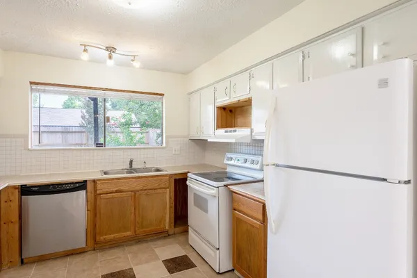 a kitchen with a sink a stove a refrigerator a washer dryer and white cabinets