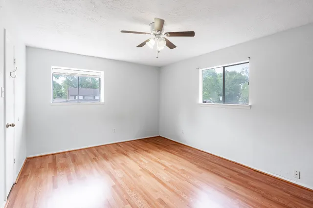 a view of empty room with wooden floor and fan