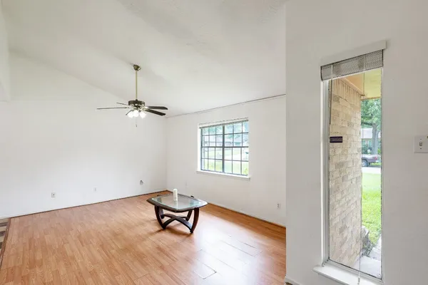 a view of a room with wooden floor a ceiling fan and windows