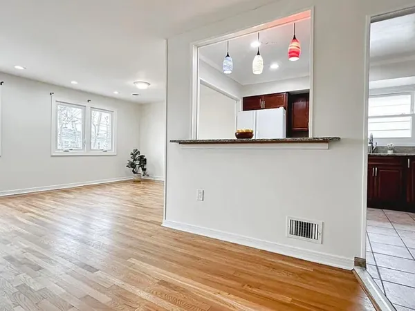a view of an empty room with window and wooden floor