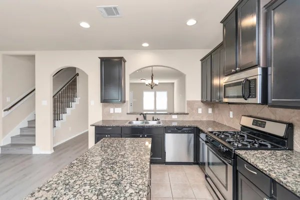 a large kitchen with stainless steel appliances granite countertop a stove a sink and a microwave