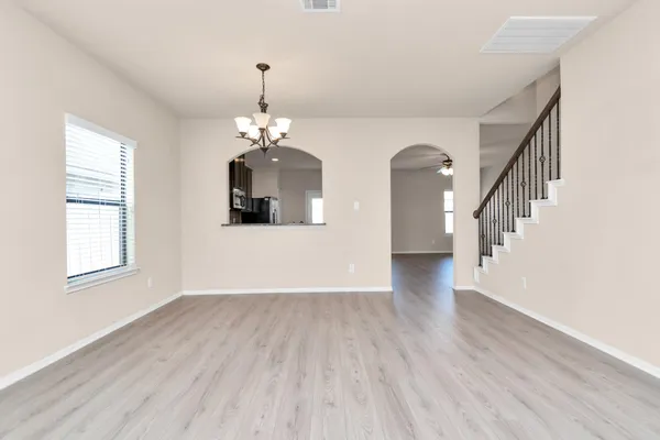 a view of a room with wooden floor chandelier and windows
