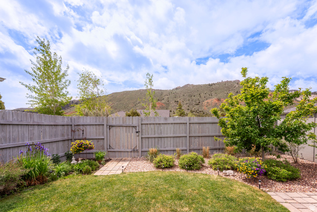7343 North Sawtooth Cv Road Vernal, UT 84078 - Photo 33 of 64 Fenced backyard featuring a manicured lawn, established landscaping, a stepping stone pathway, and a mountain backdrop