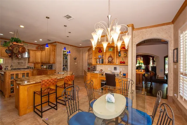a kitchen with stainless steel appliances kitchen island granite countertop a table chairs and a refrigerator