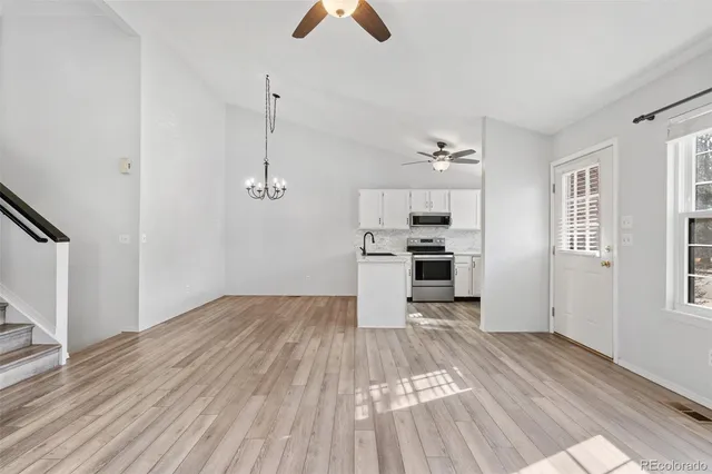 a view of kitchen and empty room with wooden floor