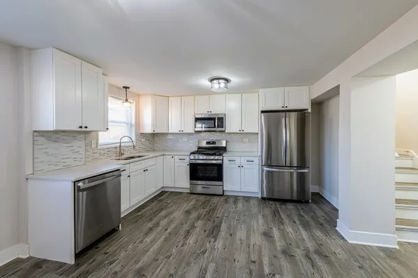 a kitchen with a refrigerator a stove top oven a sink and dishwasher with wooden floor