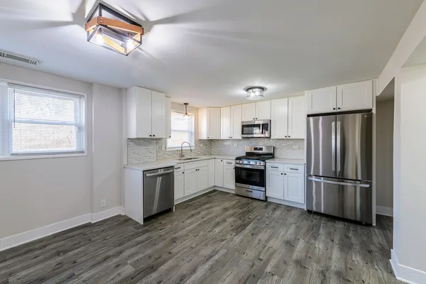 a kitchen with granite countertop stainless steel appliances a refrigerator cabinets and wooden floor