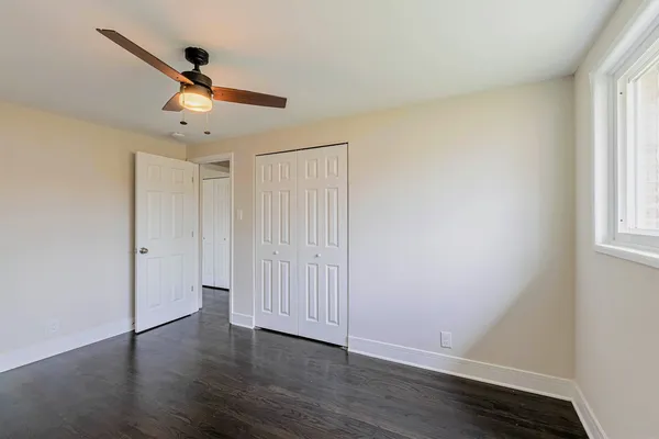 an empty room with wooden floor fan and windows