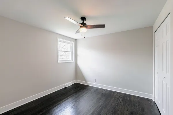 an empty room with wooden floor ceiling fan and windows