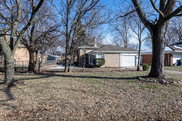 a view of a house with a yard and large tree