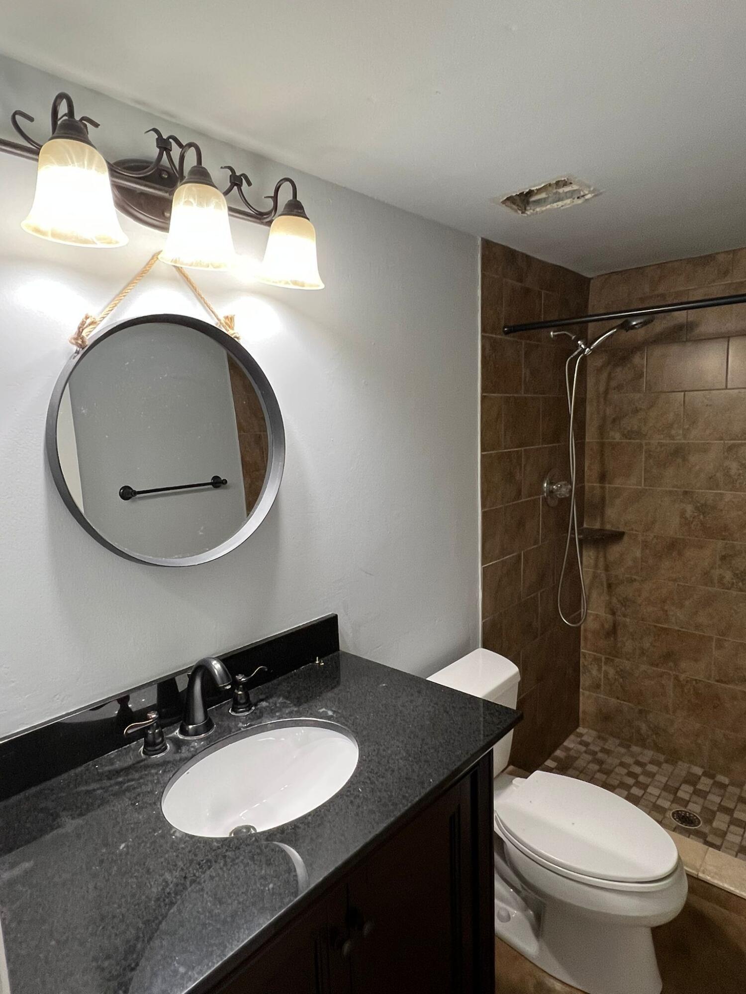 2335 Southwest 22nd Avenue, Unit 1030 Delray Beach, FL 33445 - Photo 16 of 41 a bathroom with a granite countertop toilet sink and mirror