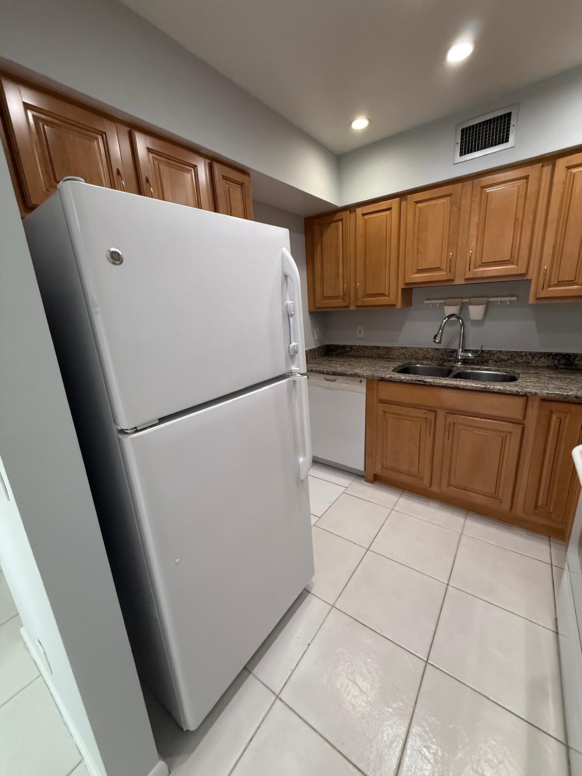 2335 Southwest 22nd Avenue, Unit 1030 Delray Beach, FL 33445 - Photo 7 of 41 a kitchen with stainless steel appliances granite countertop a refrigerator sink and cabinets