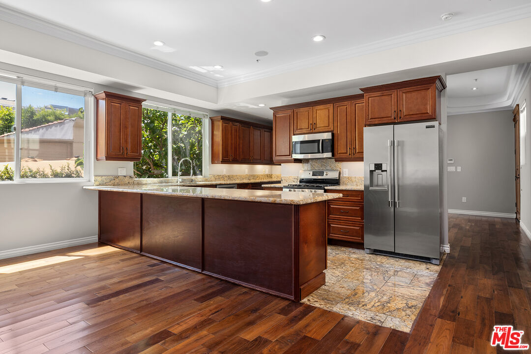 632 North Kings Road, Unit 102 West Hollywood, CA 90048 - Photo 2 of 13 a kitchen with granite countertop wooden floors stainless steel appliances a window and a counter space