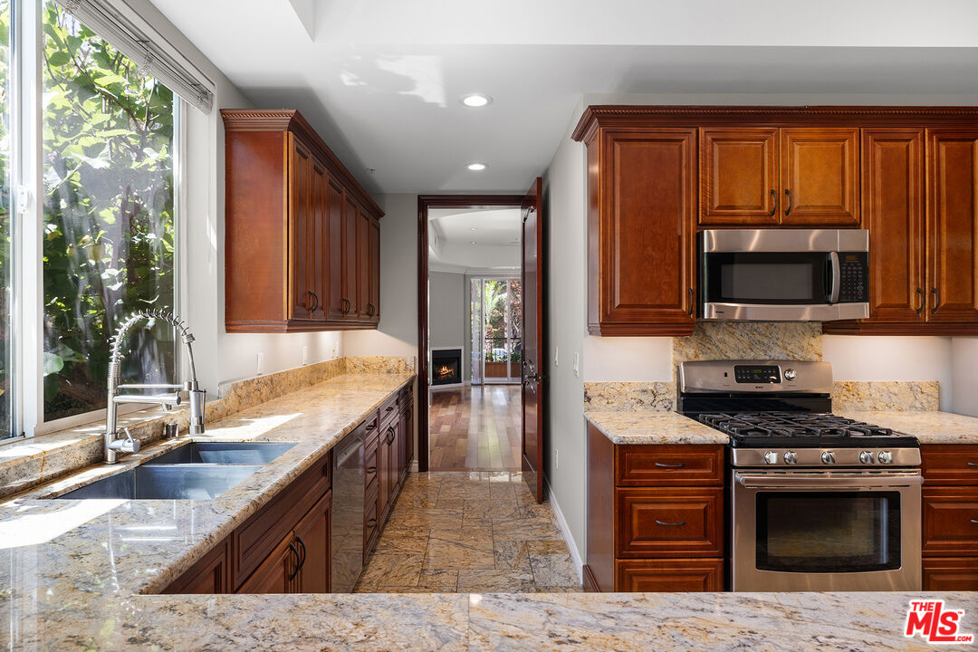 632 North Kings Road, Unit 102 West Hollywood, CA 90048 - Photo 3 of 13 a kitchen with stainless steel appliances granite countertop a stove a sink and a microwave