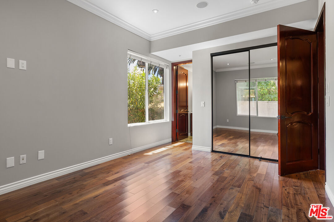 632 North Kings Road, Unit 102 West Hollywood, CA 90048 - Photo 8 of 13 an empty room with wooden floor and windows