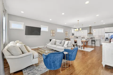 a living room with furniture kitchen view and a wooden floor