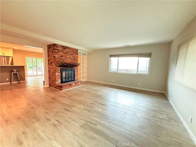 a view of empty room with wooden floor and fireplace