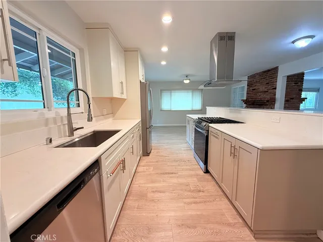 a large kitchen with kitchen island a sink a counter top space and stainless steel appliances