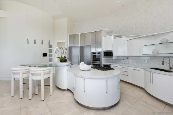 a kitchen with stainless steel appliances a sink a stove a refrigerator cabinets and chairs