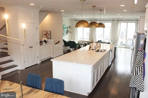 a kitchen with stainless steel appliances granite countertop a sink a stove a refrigerator and a dining table with wooden floor