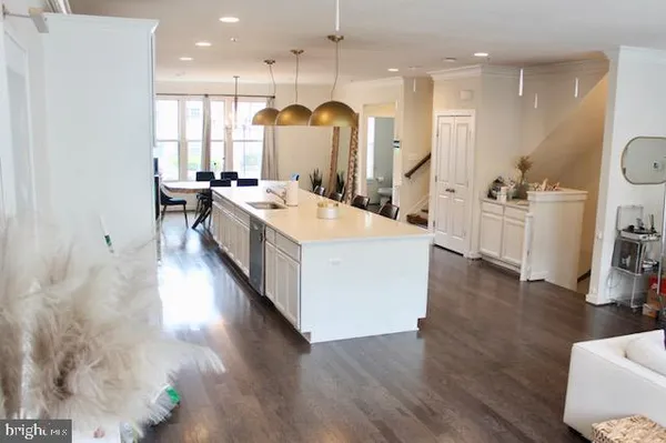 a large white kitchen with wooden floor and a sink