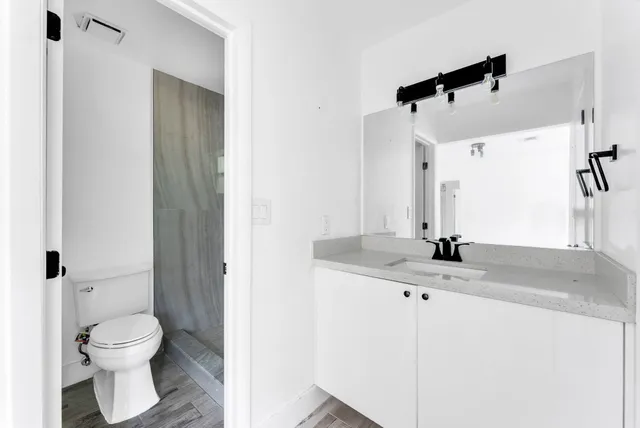 a bathroom with a granite countertop sink toilet and shower