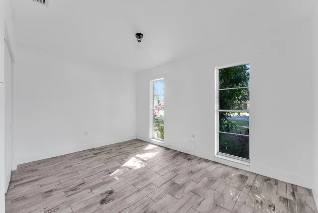 an empty room with wooden floor and windows