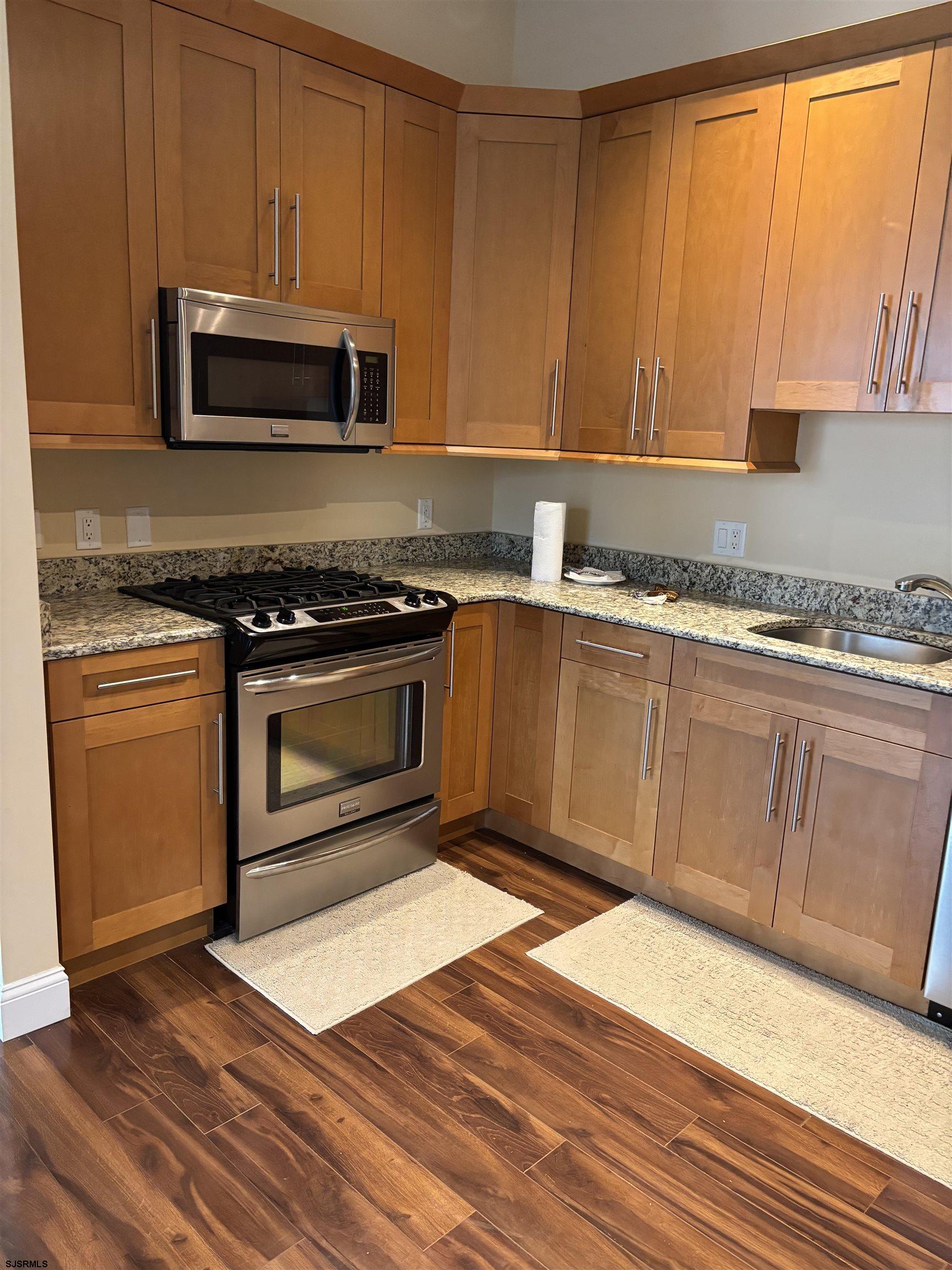 1 Mechanic Street, Unit 108 Absecon, NJ 08201 - Photo 16 of 28 a kitchen with granite countertop wooden cabinets stainless steel appliances and a window