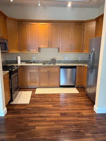 a kitchen with granite countertop wooden floors stainless steel appliances and sink