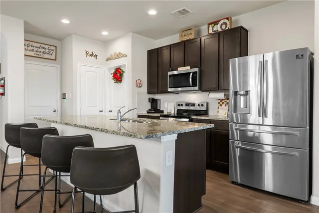 a kitchen with stainless steel appliances granite countertop a refrigerator a stove a sink and a microwave