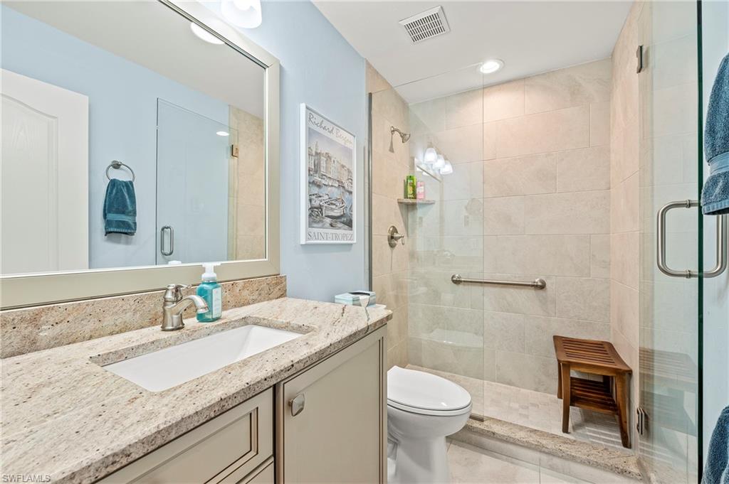 26901 Clarkston Drive, Unit 106 Bonita Springs, FL 34135 - Photo 17 of 24 a bathroom with a granite countertop sink a toilet a mirror and shower