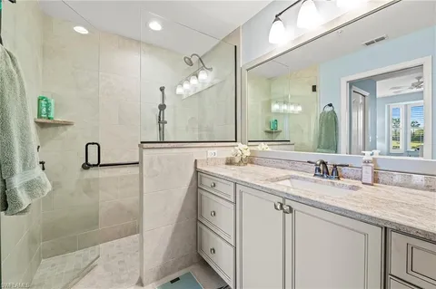 a bathroom with a granite countertop sink a mirror and a shower