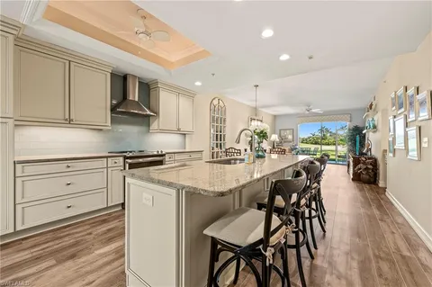 a kitchen with stainless steel appliances kitchen island granite countertop a table chairs sink and cabinets