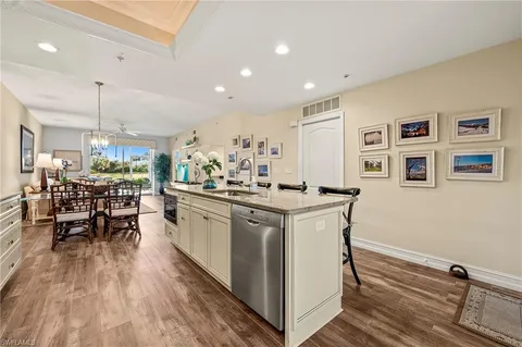 a kitchen with stainless steel appliances granite countertop a dining table chairs stove and white cabinets